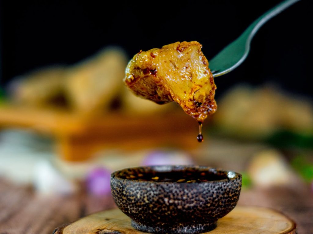 A flavorful meatball dipped in sauce captured with rich depth of field and food photography techniques.